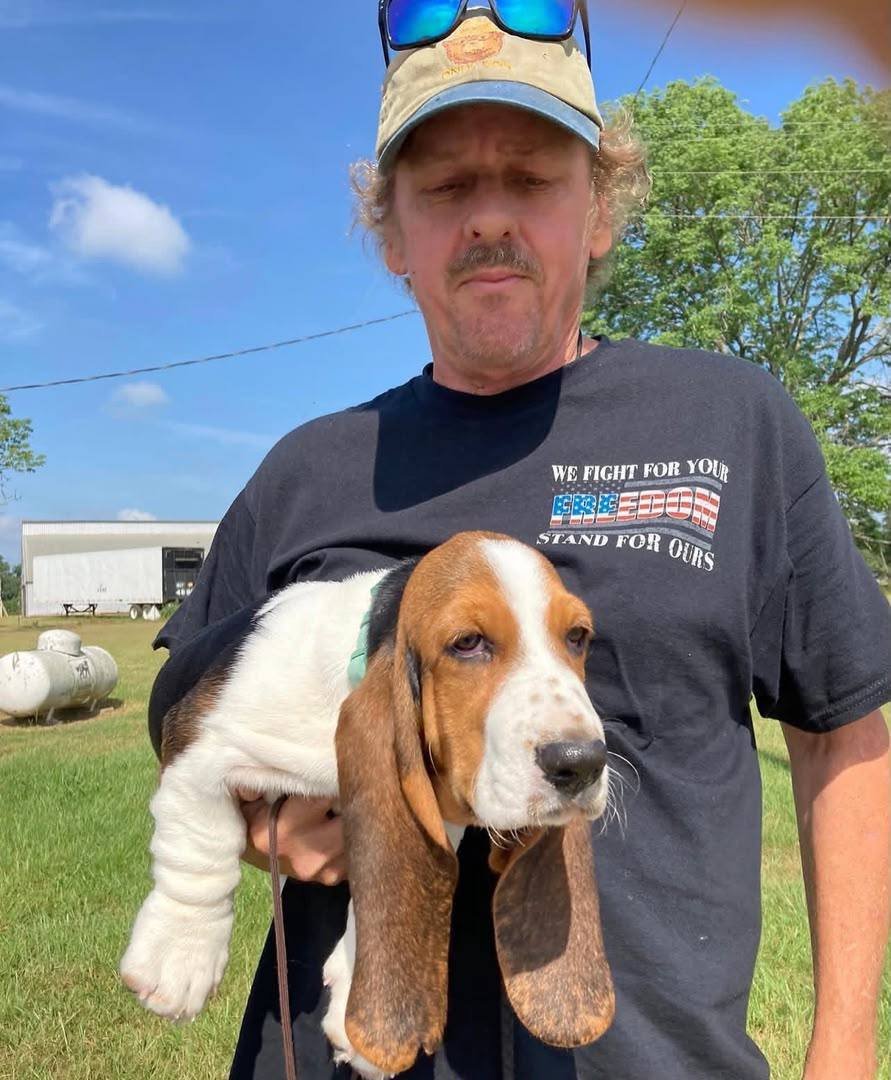 Customer outdoors holding his basset hound puppy