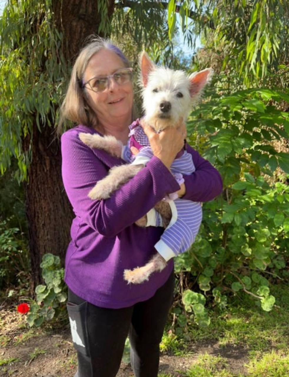 Customer holding her white terrier in the garden
