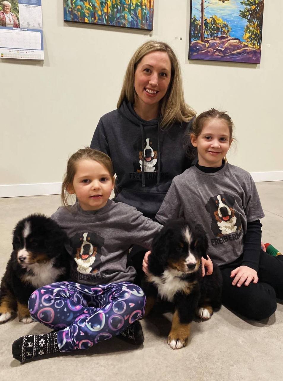 A mother and two children with two Bernese mountain dog puppies