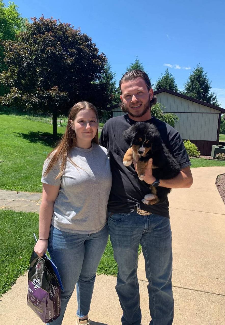 A couple outdoors holding their new puppy