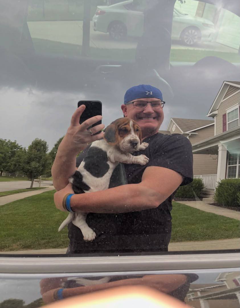 Customer holding a black and white puppy in his car