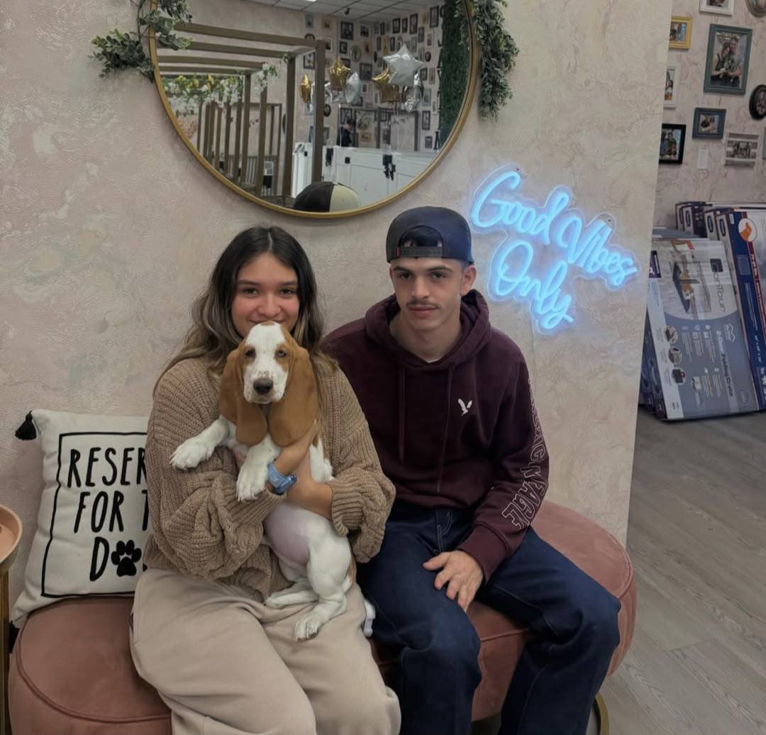 A couple at home with their basset hound puppy